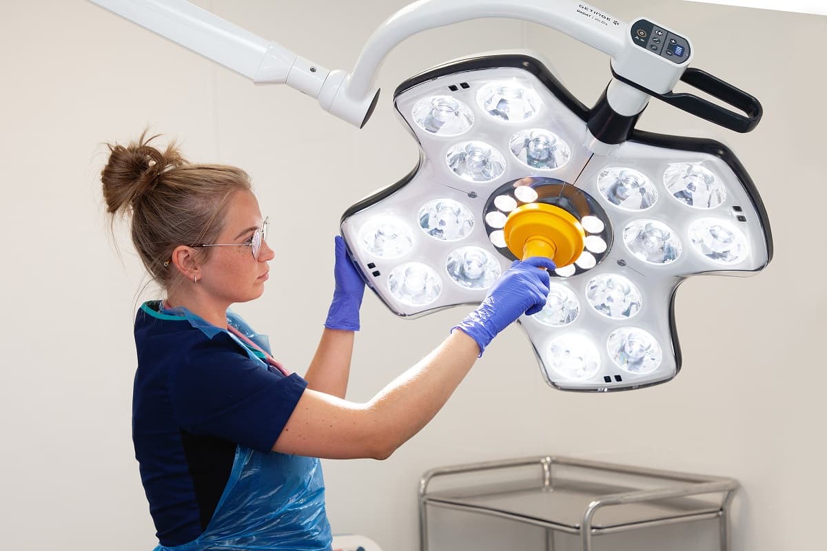 A vet preparing a surgical lamp in an operating theatre
